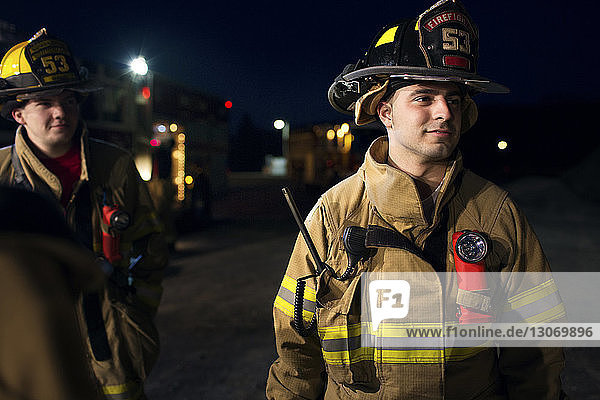 Feuerwehrmann schaut weg  während er nachts einem Kollegen zur Seite steht