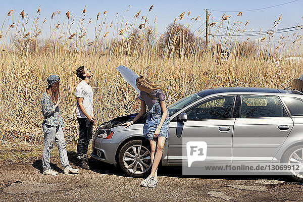 Friends standing by car on road