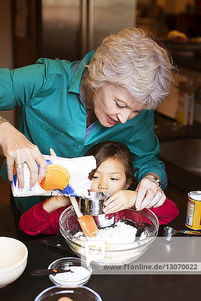 Ältere Frau mit Enkelin bereitet zu Hause Essen zu