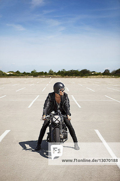 Mann sitzt auf Motorrad auf Feld gegen Himmel