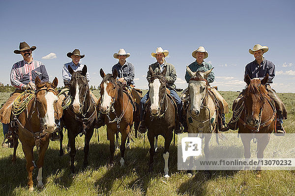 Portrait of cowboys sitting on horse against sky
