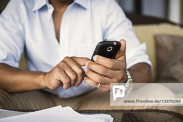 Midsection of man using mobile phone while sitting on sofa in porch
