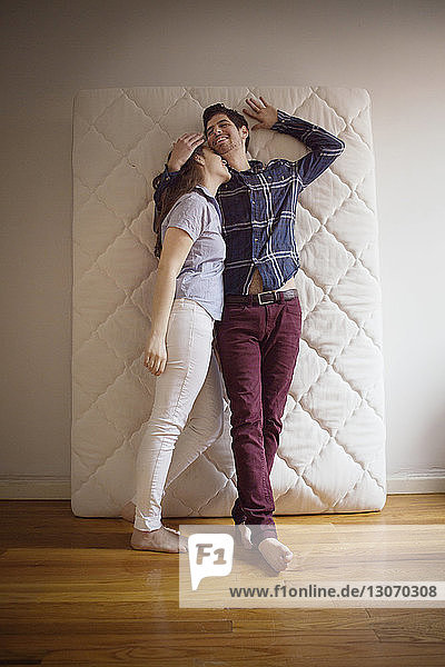 Paar lehnt auf Matratze  während es zu Hause an der Wand steht