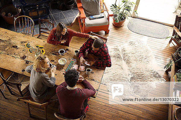 High angle view of friends playing cards while having coffee at home