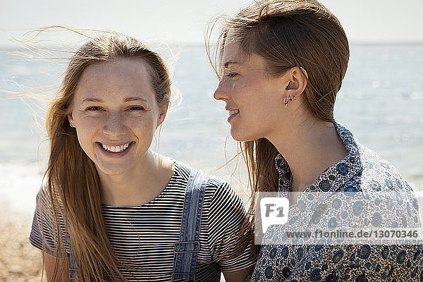 Portrait of smiling woman with friend on beach