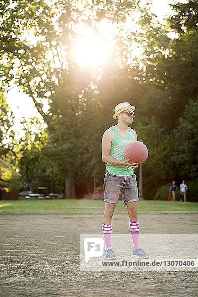 Mann hält Völkerball  während er an einem sonnigen Tag auf dem Spielfeld steht