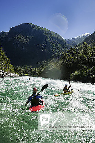 Freunde kajakfahren im Fluss gegen den Himmel an einem sonnigen Tag