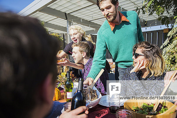 Man serving food to friends during garden party