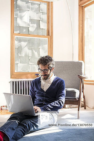 Mann benutzt Laptop-Computer  während er zu Hause sitzt