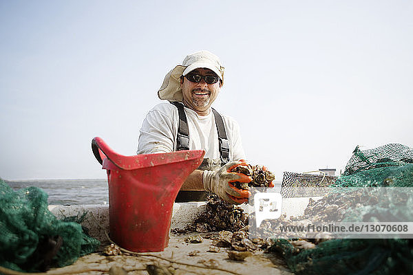 Porträt eines Arbeiters in einer Austernzucht vor klarem Himmel
