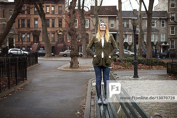 Woman standing on bench and looking up