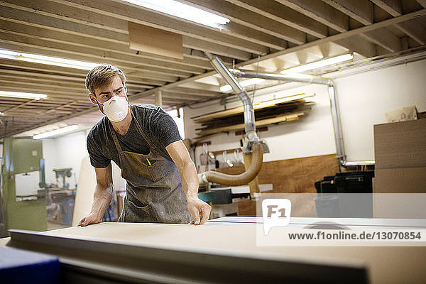 Mann justiert Holzbrett auf dem Tisch während der Arbeit in der Werkstatt