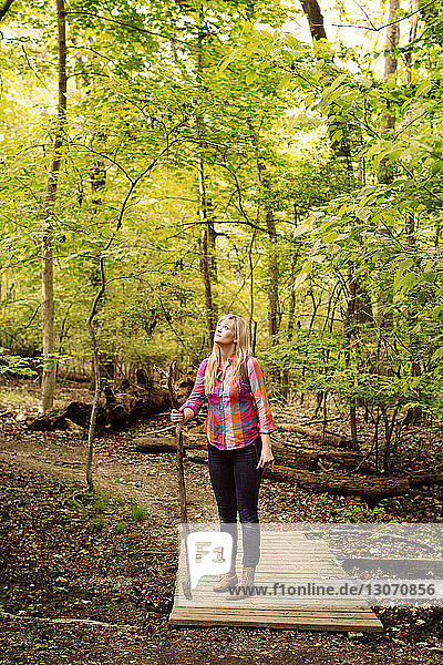 Frau schaut auf  während sie auf einem Steg im Wald steht
