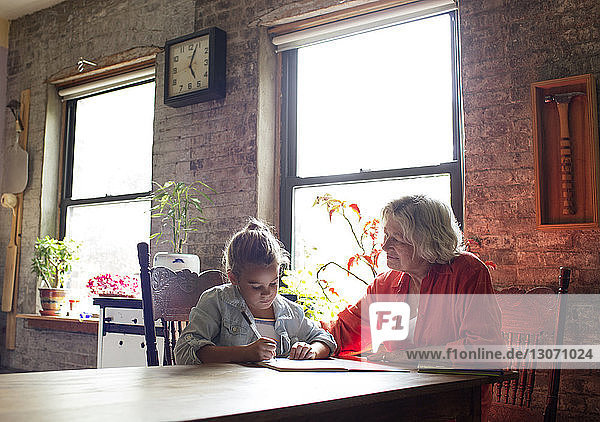 Woman guiding granddaughter in doing homework