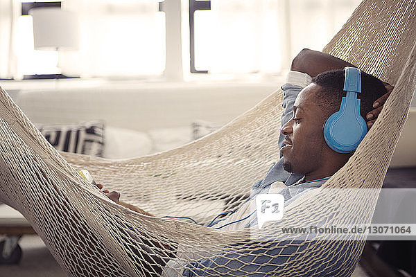 Man listening music while resting on hammock at home