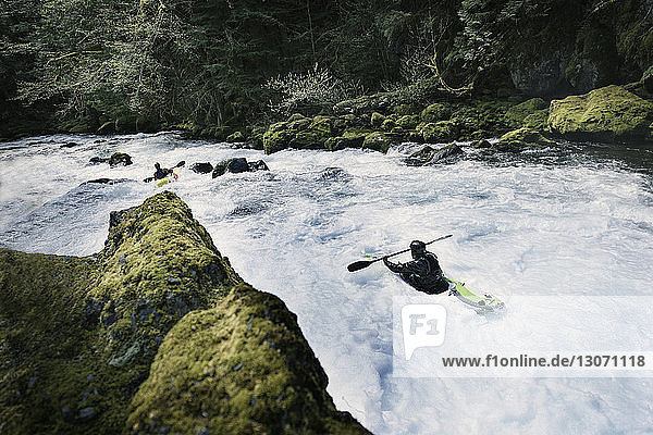Men kayaking in river at forest