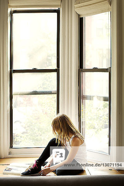 Mädchen lernt  während sie zu Hause am Fenster sitzt
