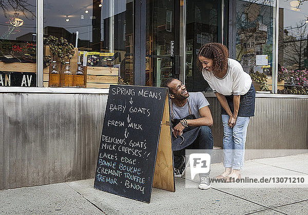 Glücklicher Mann schreibt von Frau vor Laden auf Tafel