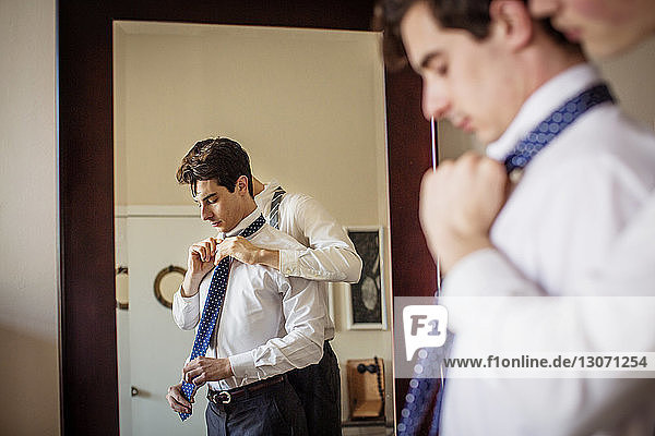 Gay man assisting boyfriend for adjusting necktie