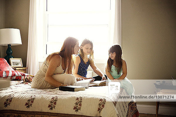 Mutter studiert Töchter  während sie zu Hause im Bett sitzt