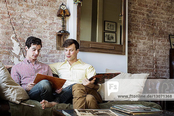 Gay men looking record while sitting on sofa at home