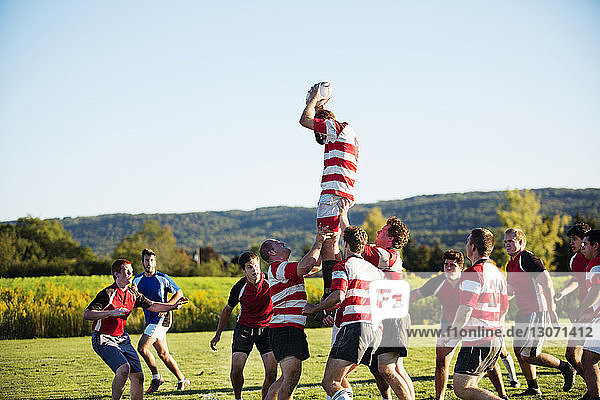 Rugby team playing on field against sky