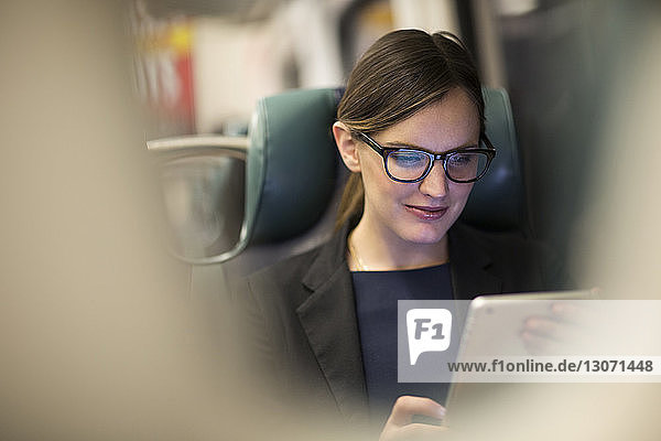 Happy businesswoman using tablet while traveling in subway train