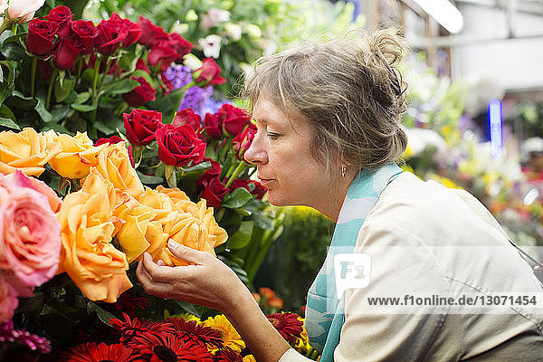 Seitenansicht einer Frau  die Blumen am Marktstand riecht