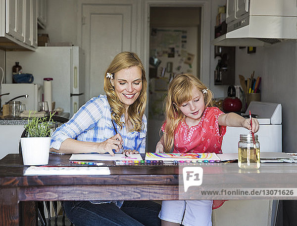 Mutter und Tochter malen zu Hause auf Buch