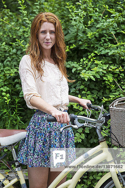 Bildnis einer Frau mit Fahrrad im Park stehend