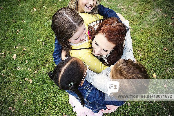 Draufsicht einer Frau  die Mädchen umarmt  während sie auf einem Grasfeld steht