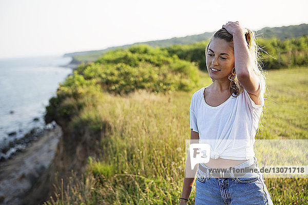 Woman with hand in hair looking down while standing on field