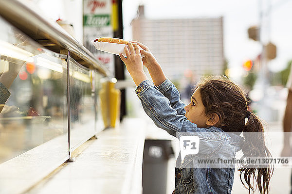 Mädchen nimmt Hot Dog vom Imbisswagen