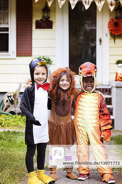 Porträt von glücklichen Freunden in Halloween-Kostüm  die vor dem Haus stehen