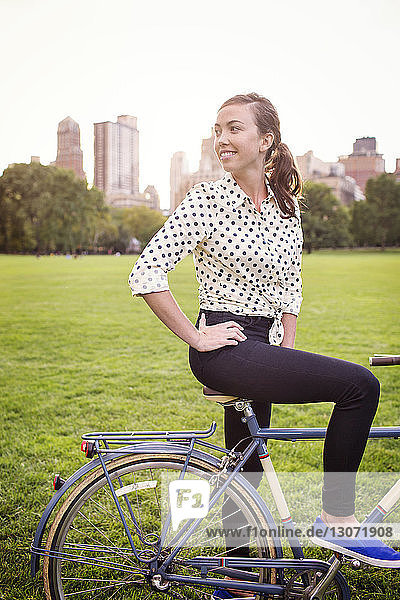 Woman looking away while standing with bicycle in Central Park