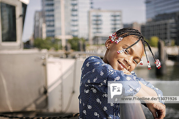 Portrait of girl leaning on railing in boat at city