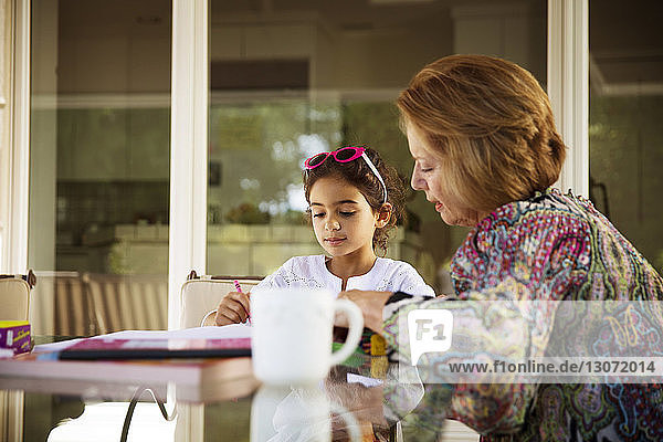 Großmutter hilft Enkelin beim Lernen am Tisch