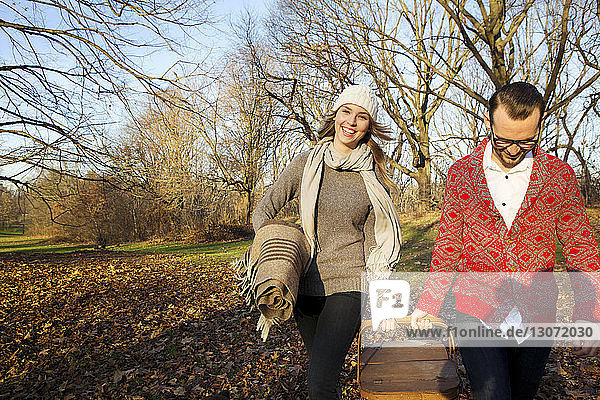 Happy couple holding basket while walking at park