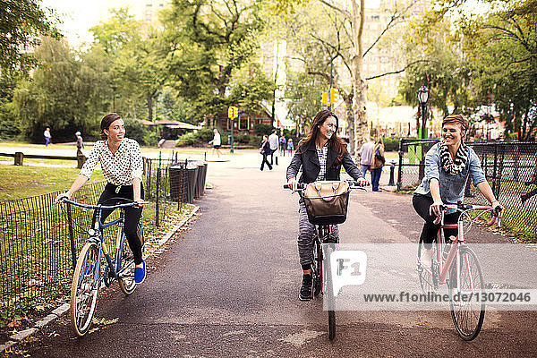 Lächelnde Freunde radeln auf der Straße im Central Park