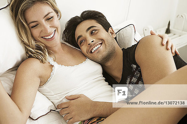 Cheerful couple lying on bed at home