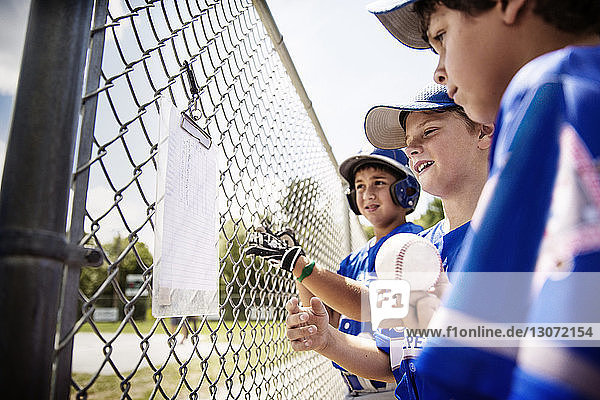 Players reading score card on fence