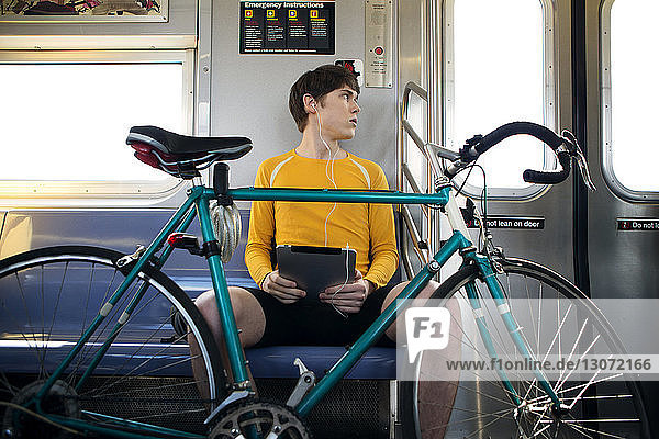 Mann mit Fahrrad schaut auf Zug  der auf Eisenbahnschiene angekommen ist