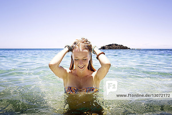 Smiling woman standing in sea against clear sky