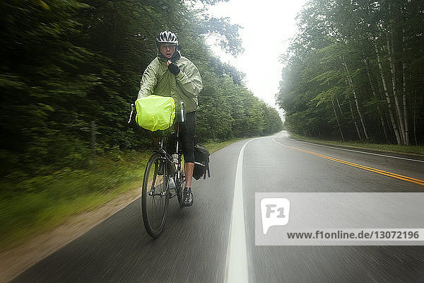 Man cycling on road amidst trees in forest