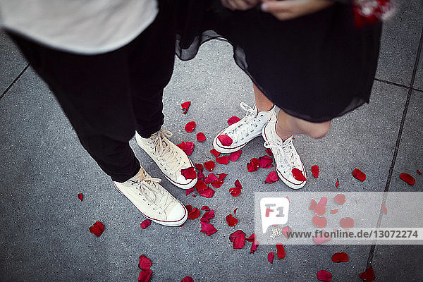Niedriger Abschnitt eines auf einem Fußweg stehenden Paares mit roten Rosenblättern