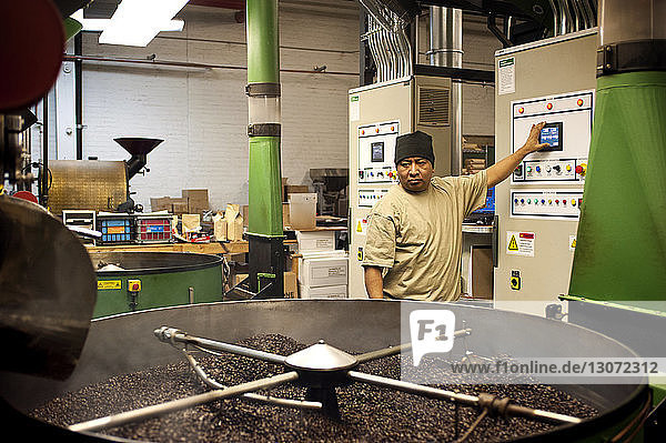 Mann bedient Maschinen  während er in der Kaffeeindustrie steht