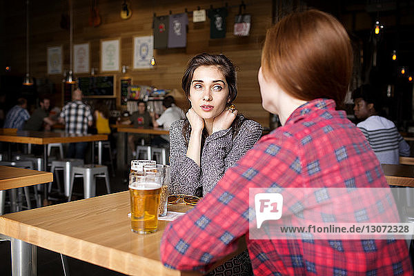 Freunde trinken Bier  während sie in einer Brauerei am Tisch sitzen