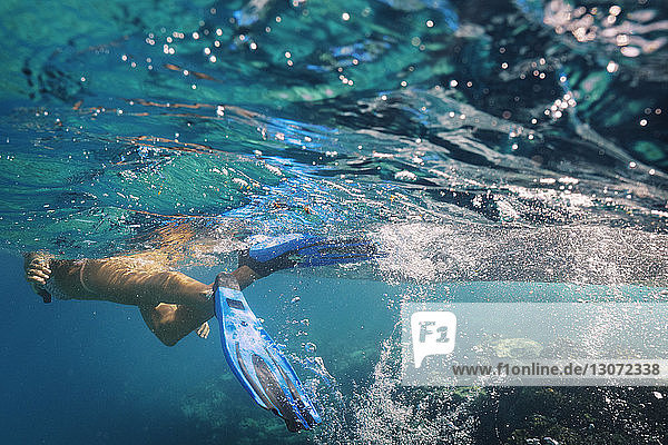 Frau mit Tauchflossen schwimmt unter Wasser