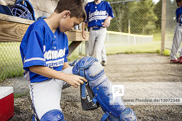 Boy wearing baseball pad in dugout