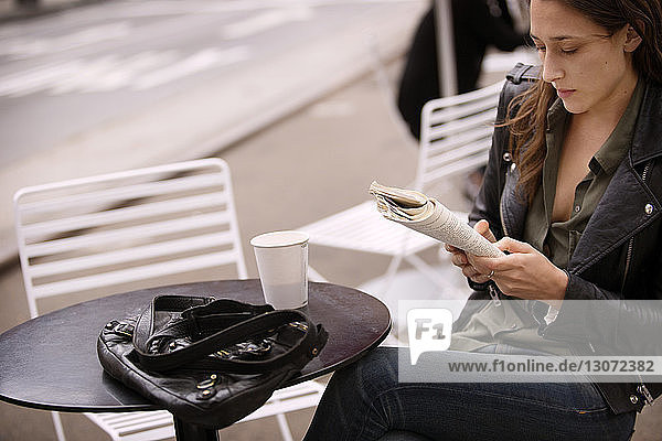 Frau liest Buch bei Kaffee im Straßencafé